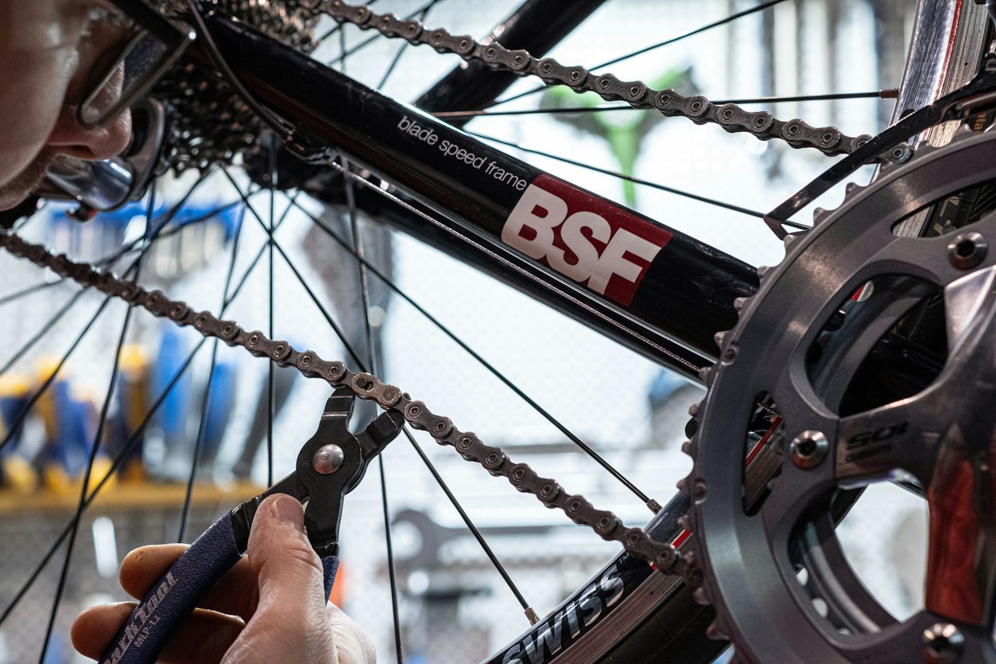 Mechanik naprawia łańcuch rowerowy za pomocą narzędzia.
